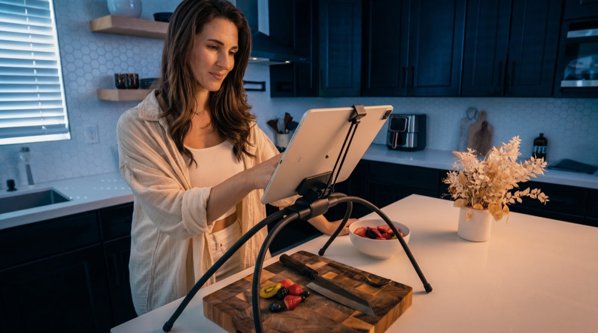 Person following a recipe on a tablet held at eye level over the kitchen counter by the Tablift MaxPro