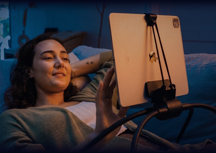 Lean back. Relax. &mdash; woman reclined in bed, iPad held at eye level by the Tablift MaxPro